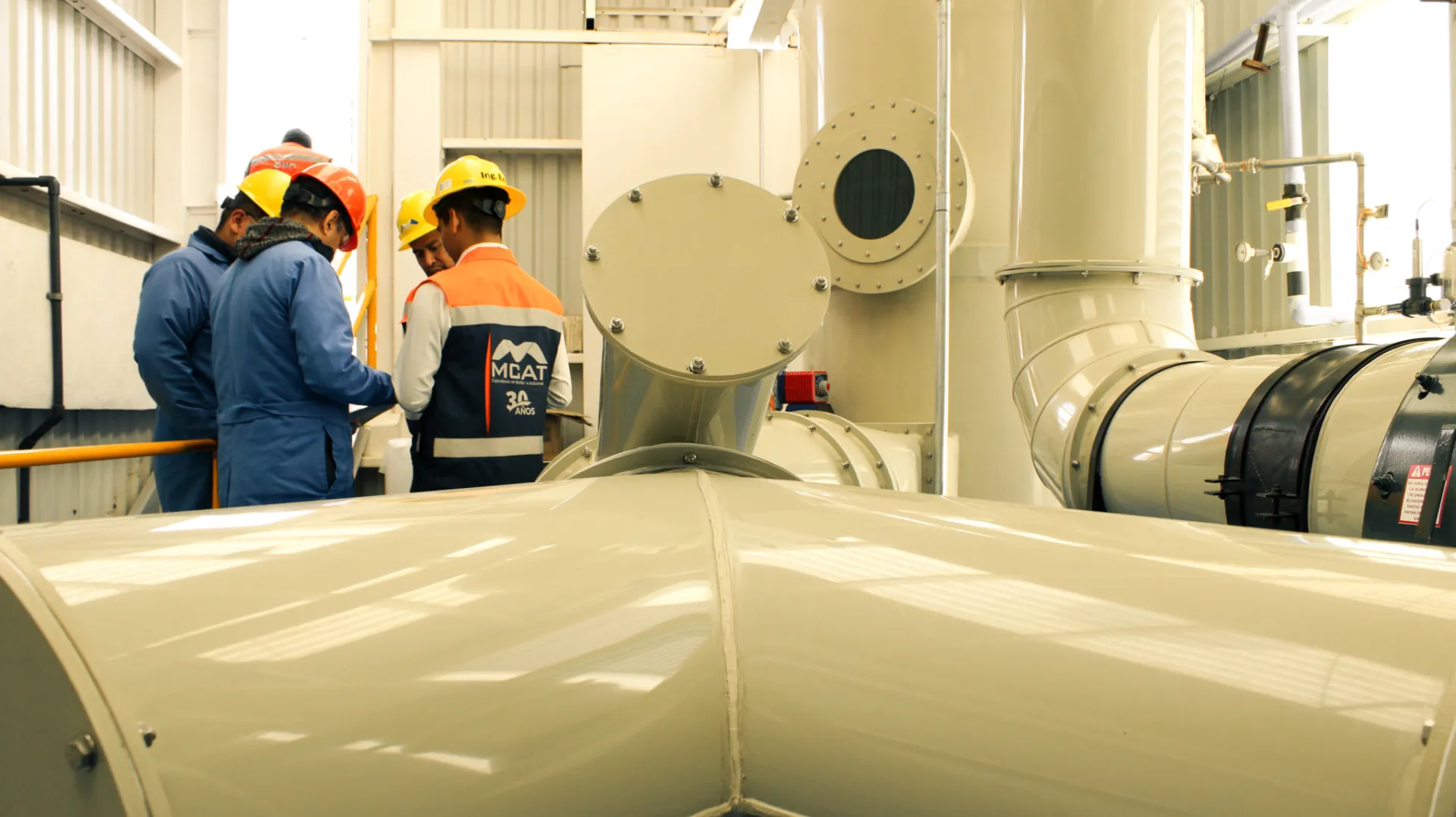 Técnicos con equipo de seguridad revisan scrubber industrial y ductería en planta